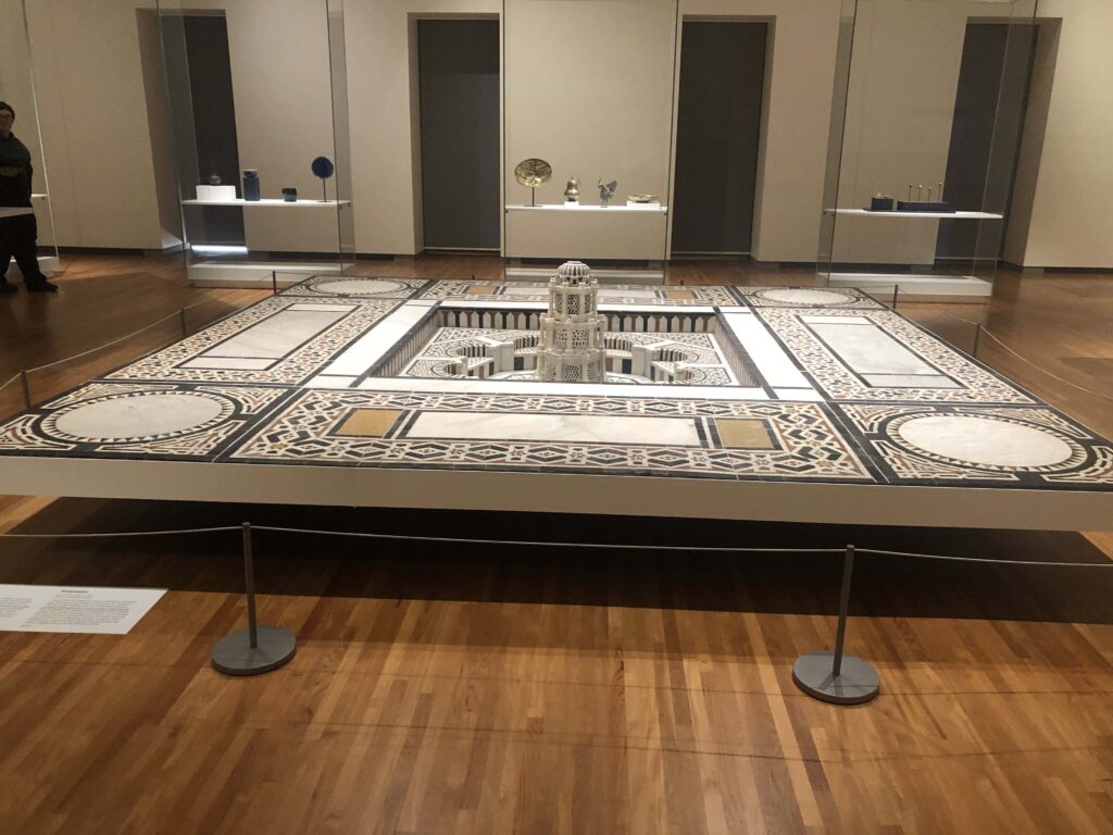 A square marble-and-mosaic fountain in a museum gallery