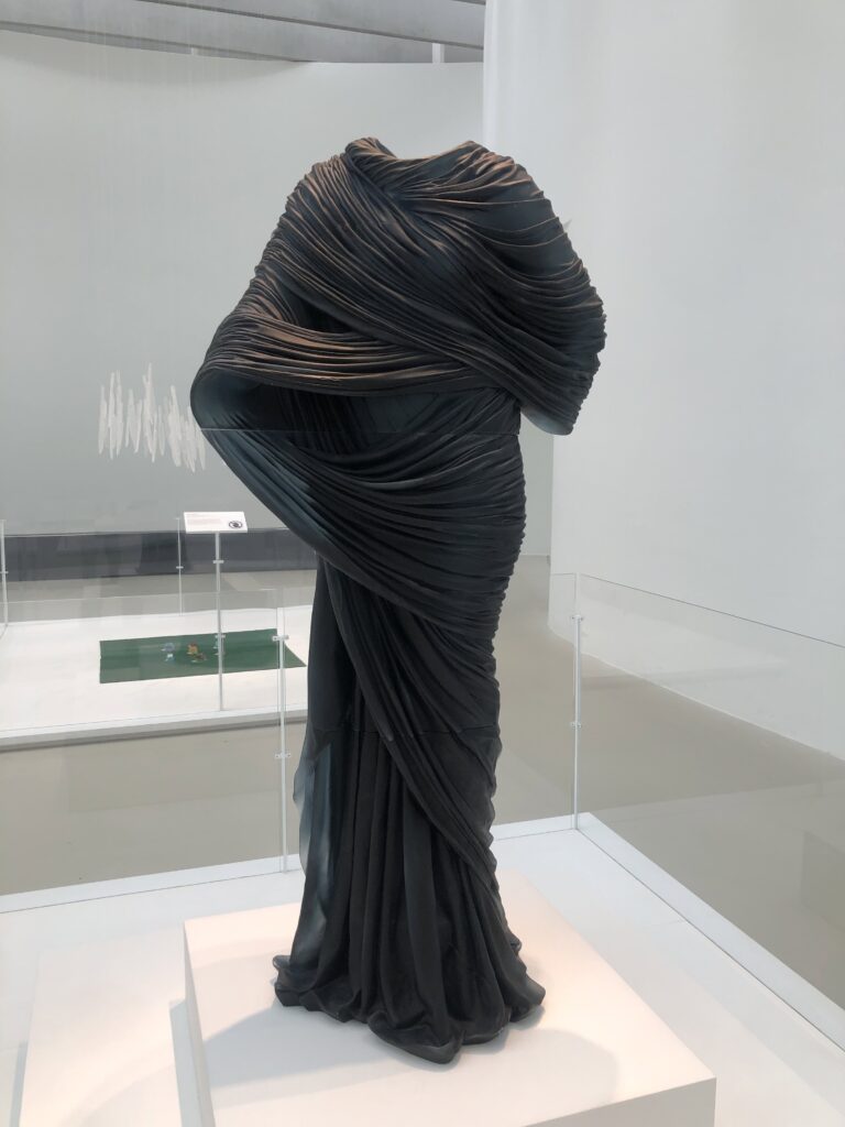 A dark glass statue of a disembodied dress