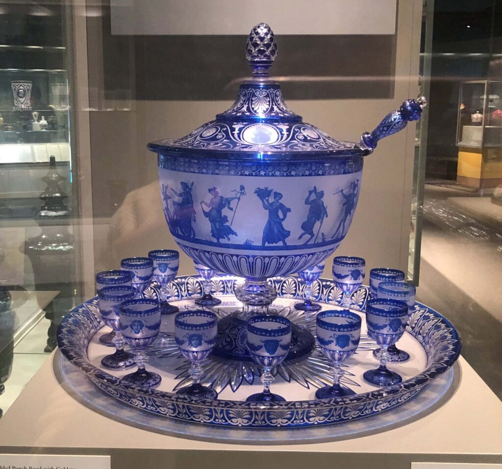 A blue-and-white glass punch bowl and glasses with cameo imagery